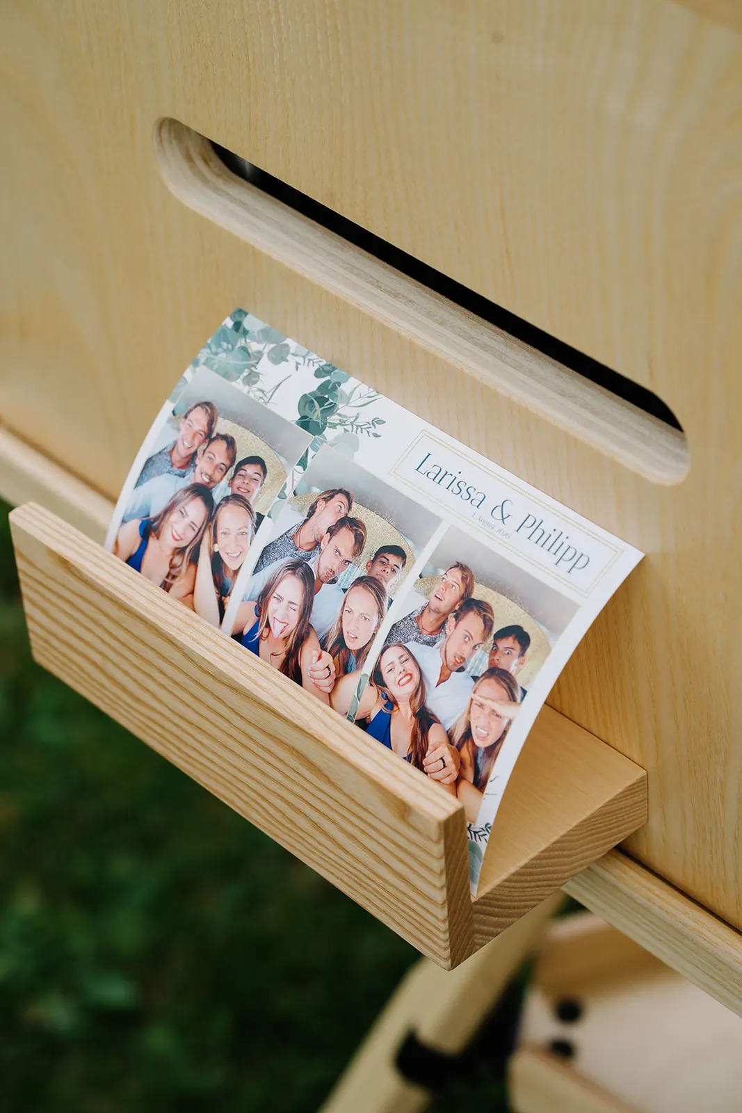 Frisch gedruckter Fotostreifen mit individuellem Layout in der Holzablage am Drucker
