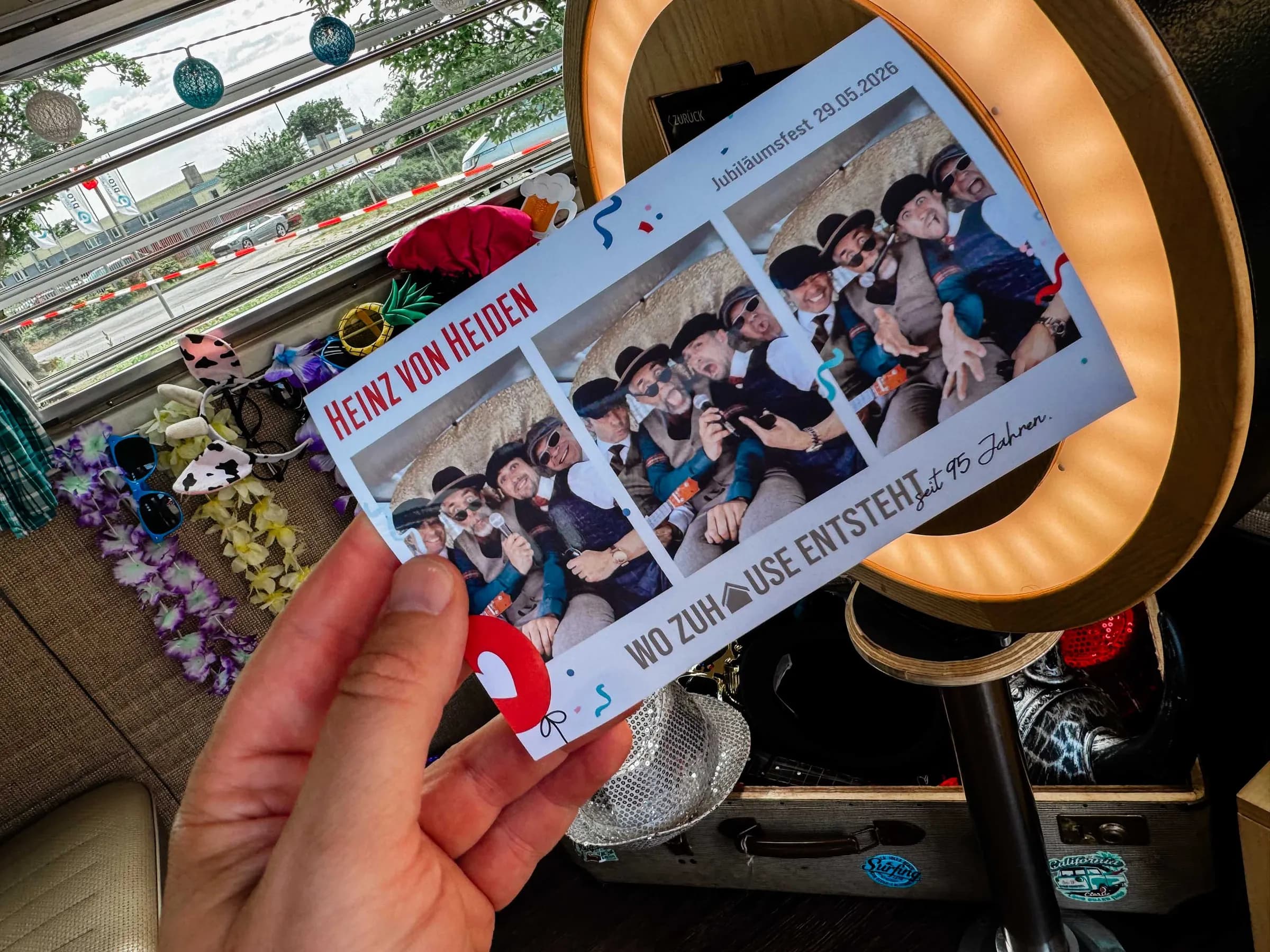 Freshly printed photo strip in hand, with the ring light and props in the Bulli behind it