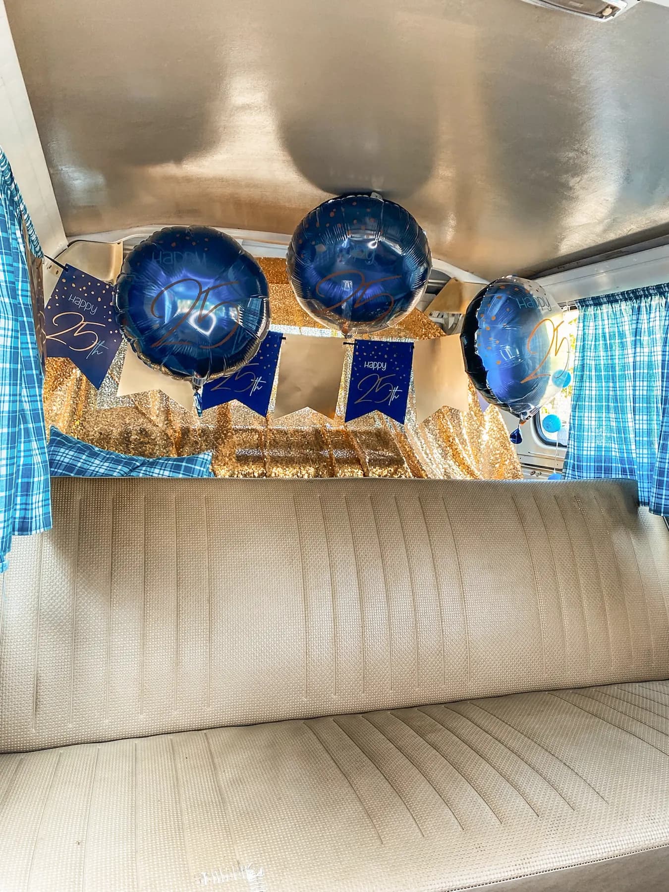 Rückbank im Bulli, geschmückt mit goldenem Pailletten-Vorhang, blauen Folienballons und Wimpelkette zum 25. Jubiläum