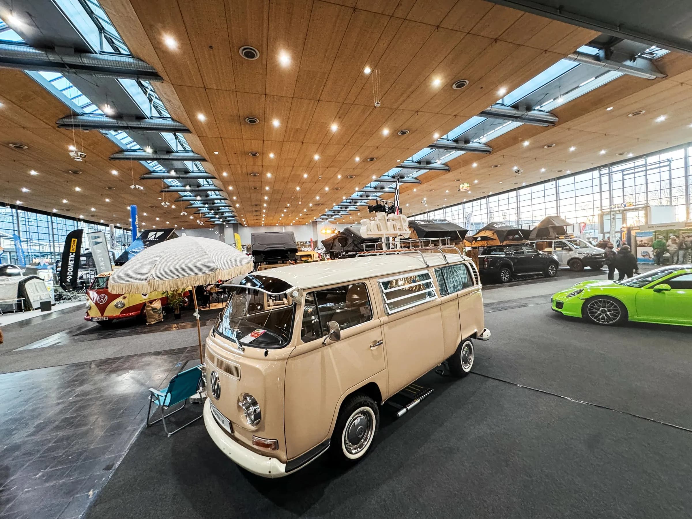 Beiger VW-Bulli als Fotobulli mit Sonnenschirm und Campingstuhl in der Messehalle der ABF Hannover, daneben andere Fahrzeuge