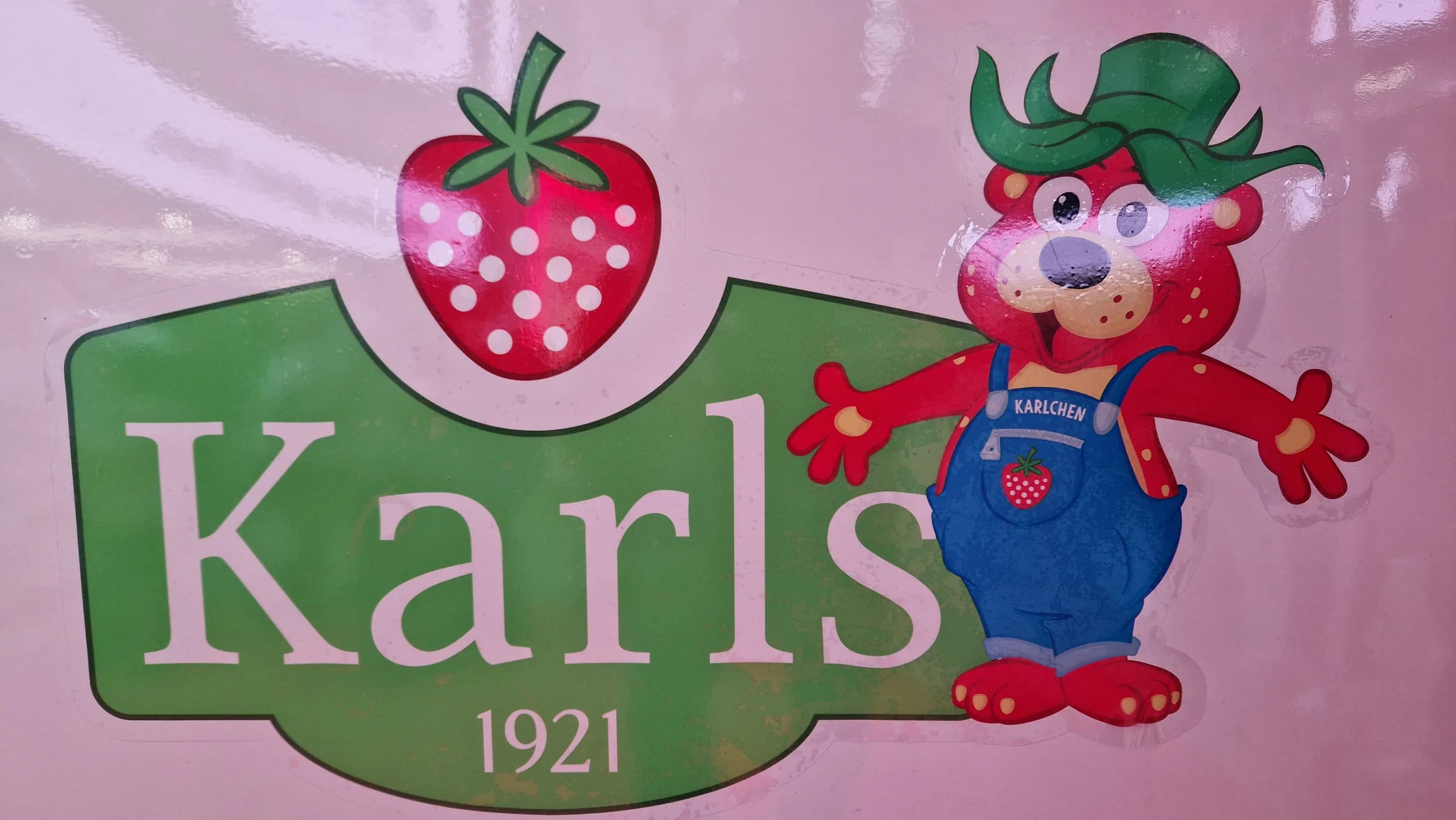 Karls logo with a strawberry and the mascot Karlchen as a sticker on the cream-coloured paintwork of the photo booth bus