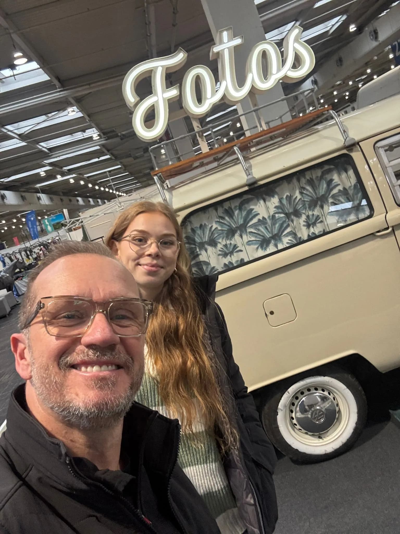 Selfie von zwei Teammitgliedern vor dem beigefarbenen Fotobulli mit Leuchtschrift „Fotos“ auf der Passion Pferd 2025