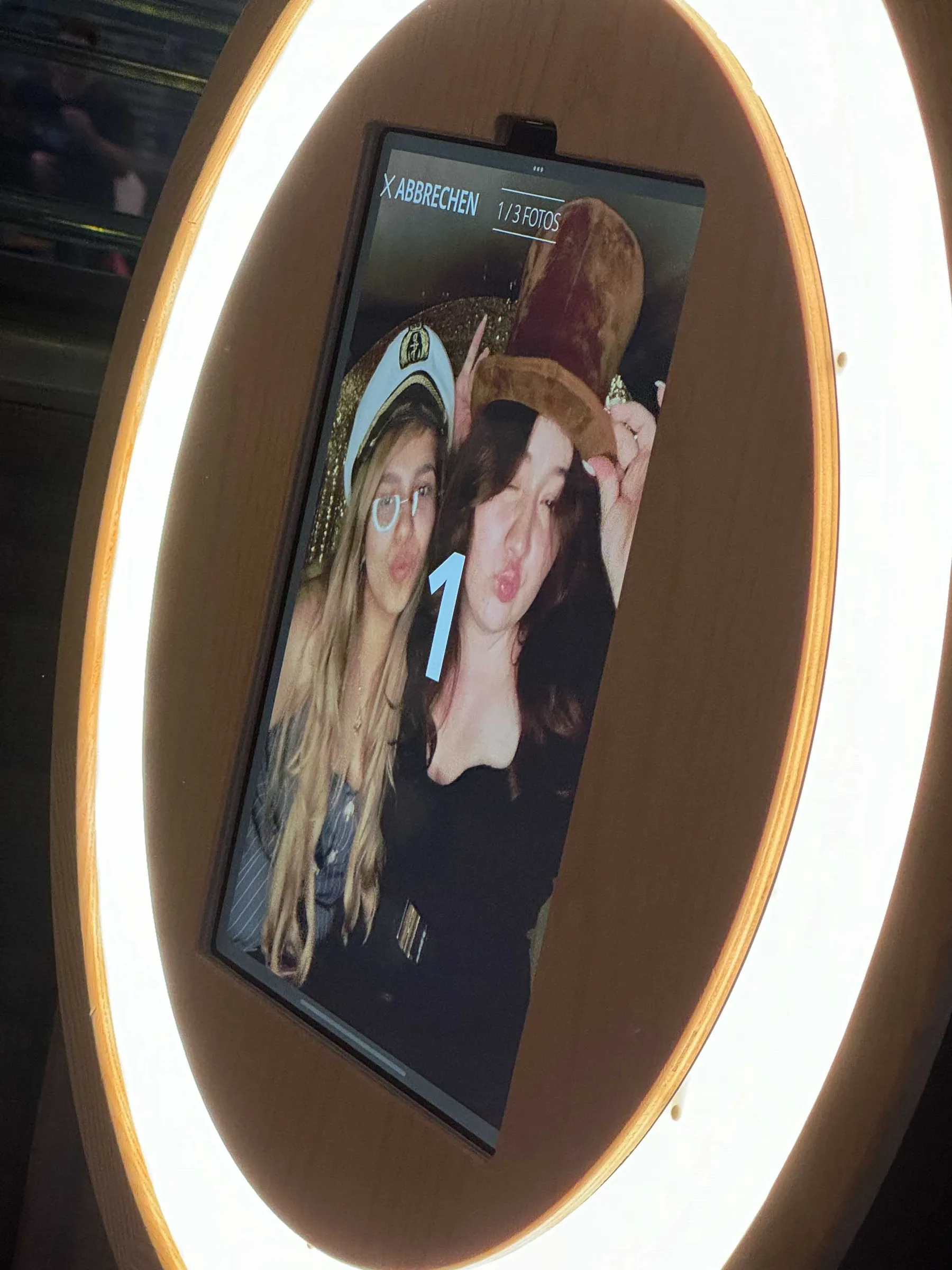 Display der Fotobox im Fotobulli mit Countdown, zwei junge Frauen mit Kapitänsmütze und Hut machen einen Kussmund