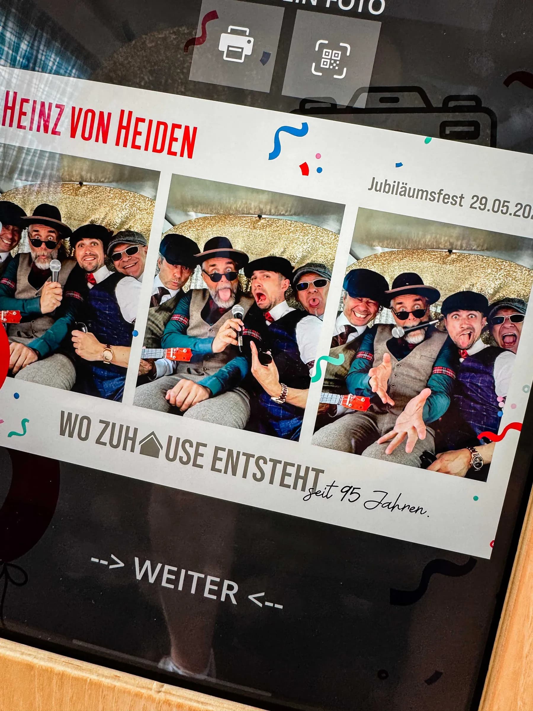 Photo booth display in the photo booth bus showing a photo strip in Heinz von Heiden design for the anniversary celebration, four men with props